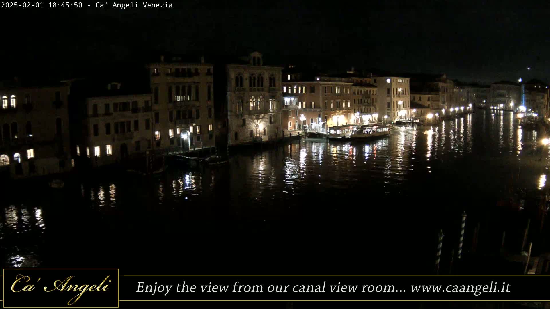 A nighttime view of a canal in Venice, with illuminated buildings reflected in the dark water.