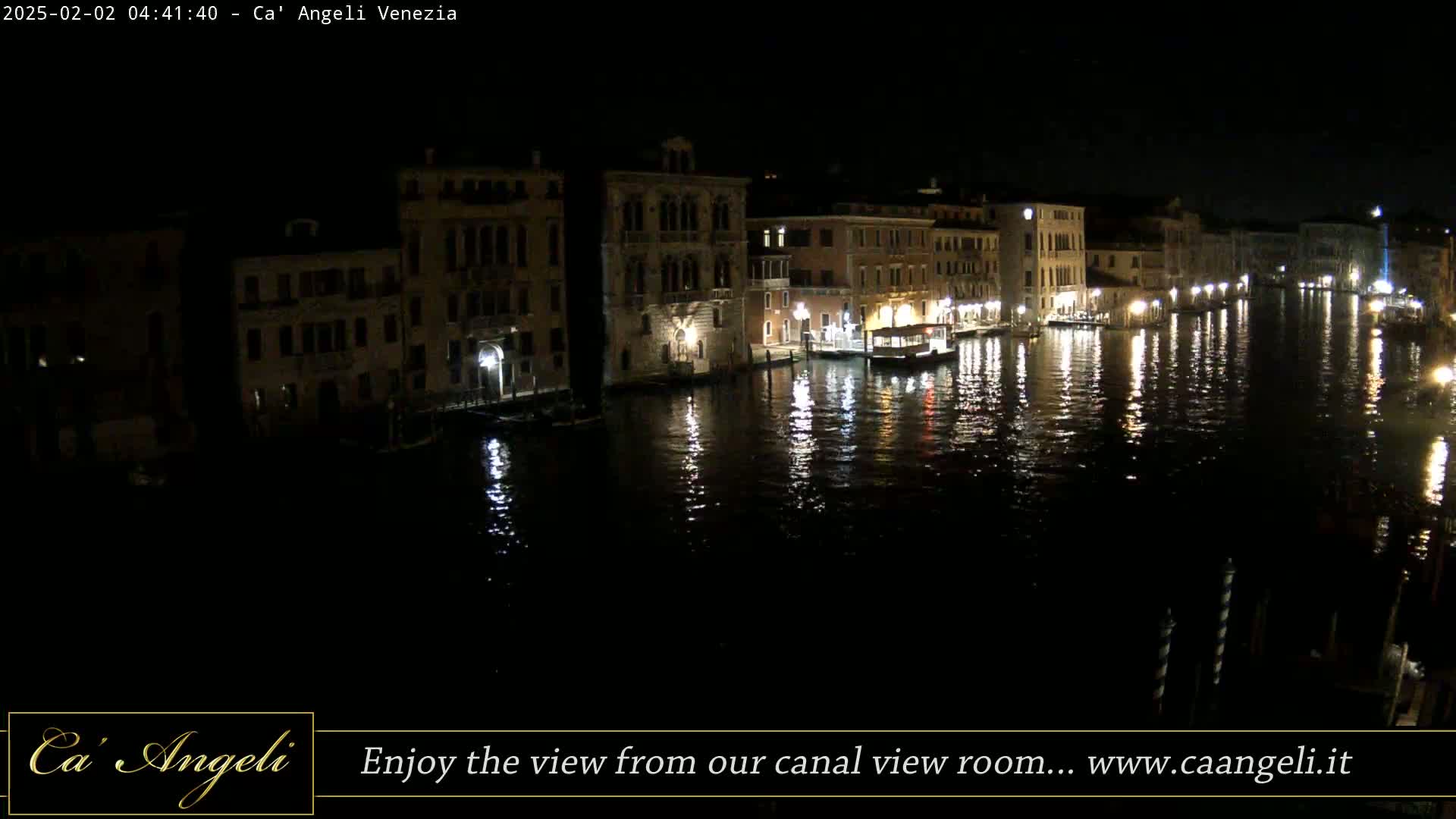 Nighttime view of a canal in Venice, Italy, with illuminated buildings lining the waterway and their reflections shimmering on the water's surface.