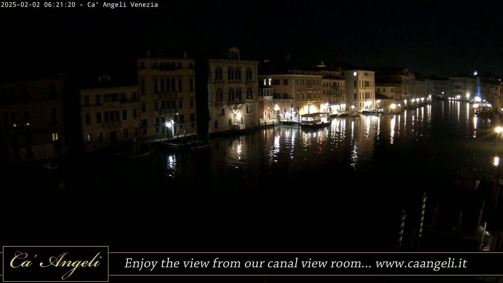 At night, a calm canal reflects the lights of buildings lining its banks.