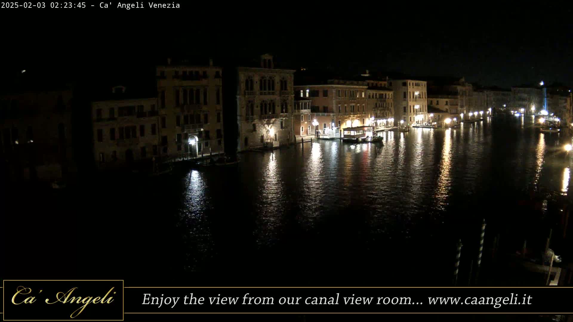 A nighttime view of a canal in Venice, with illuminated buildings lining the waterway and their lights reflecting on the calm water.