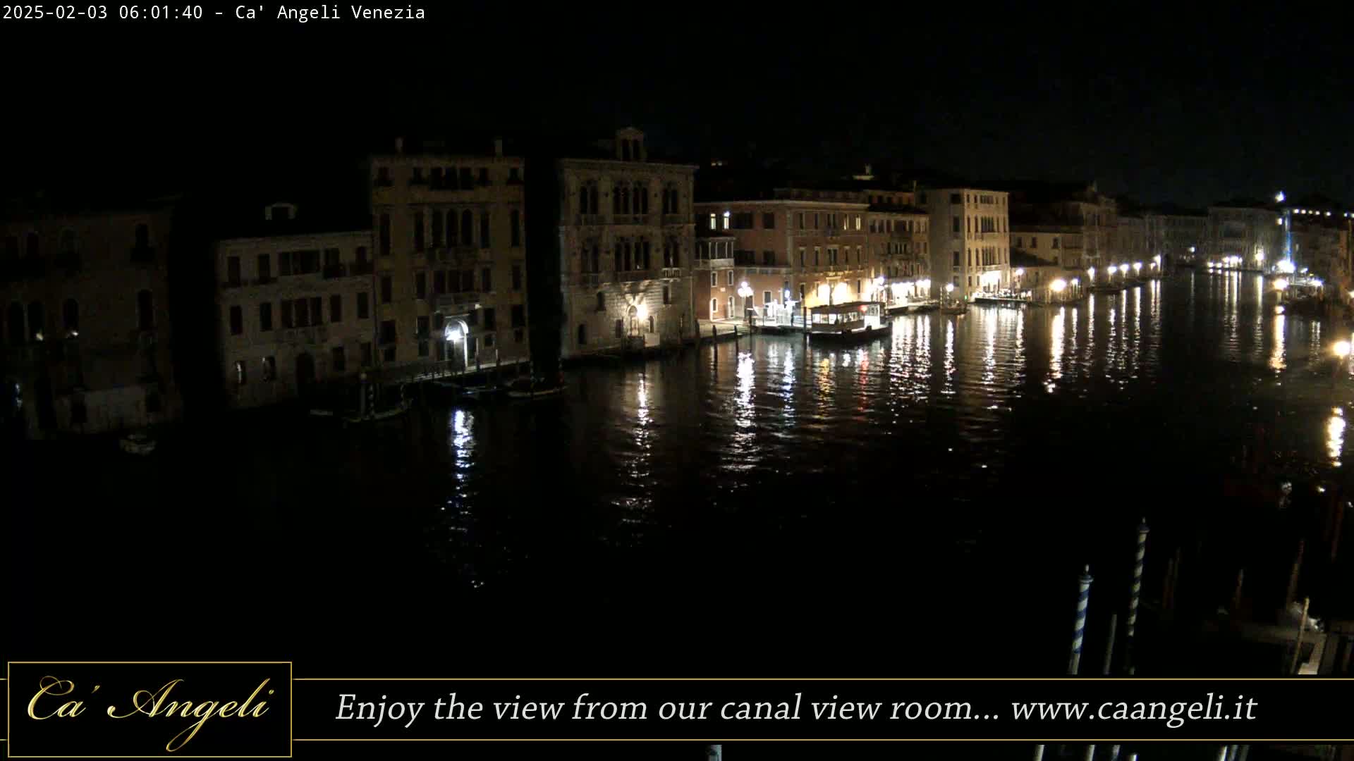 A nighttime view of a canal in Venice, Italy, shows buildings lining the waterway, their lights reflecting on the dark water.