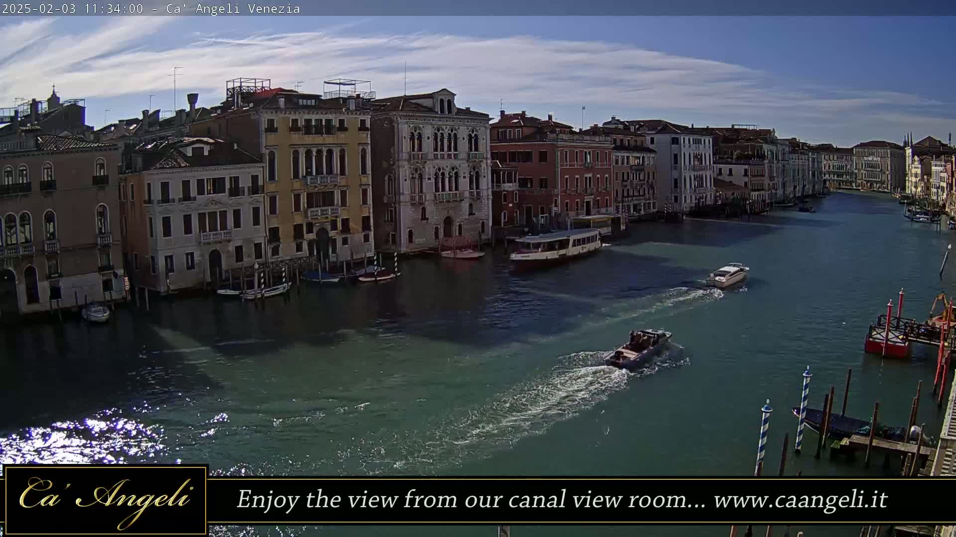 A sunny day in Venice shows several boats on a canal lined with buildings.