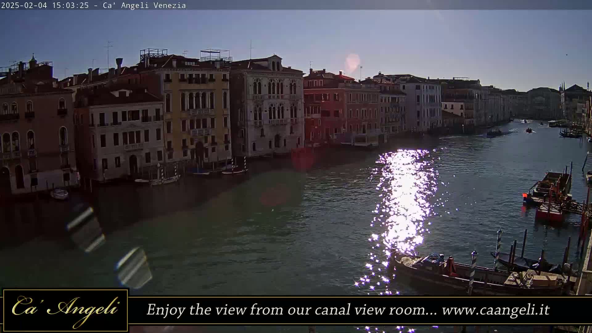 Sunlight glints on the water of a canal in Venice, reflecting off the buildings lining its banks.