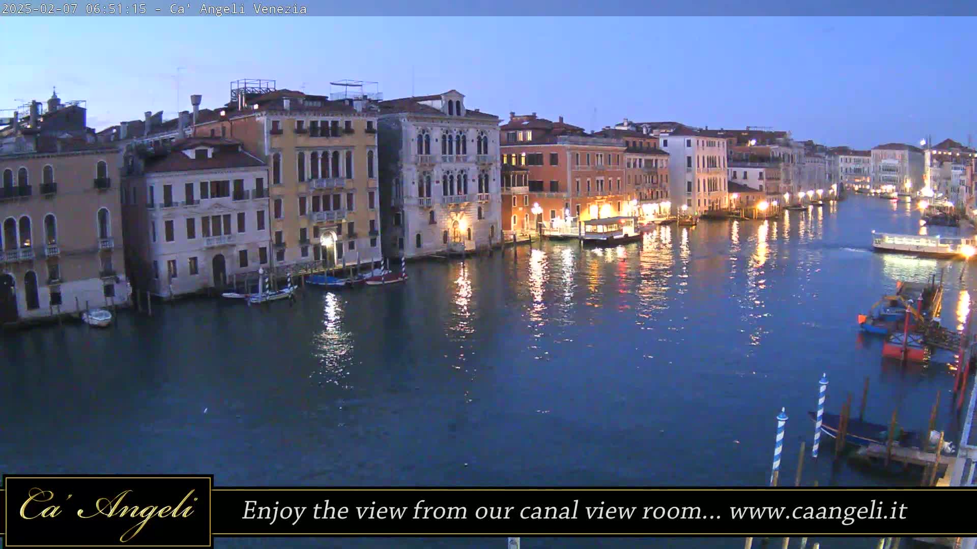 A twilight view of a Venetian canal, lined with buildings, with several boats moored along the waterway.