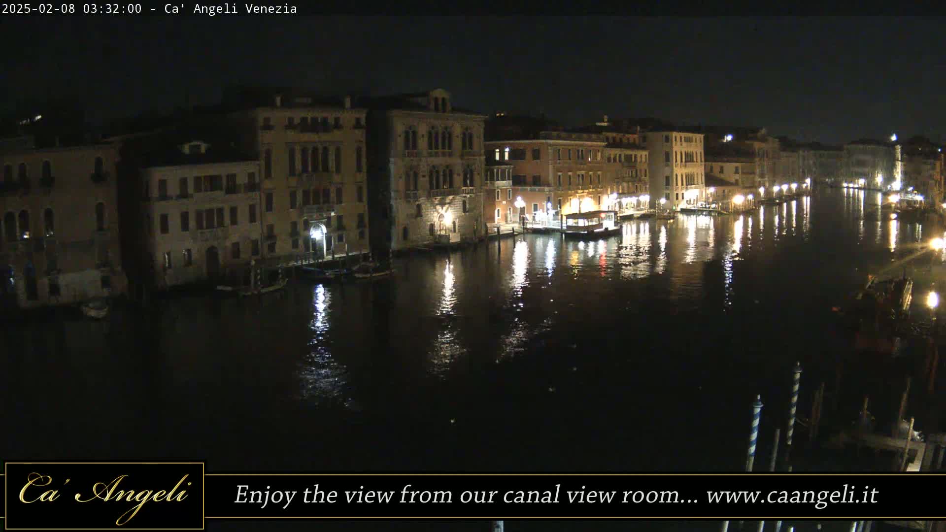A nighttime view of a canal in Venice, with buildings lining both sides, reflecting in the dark water.