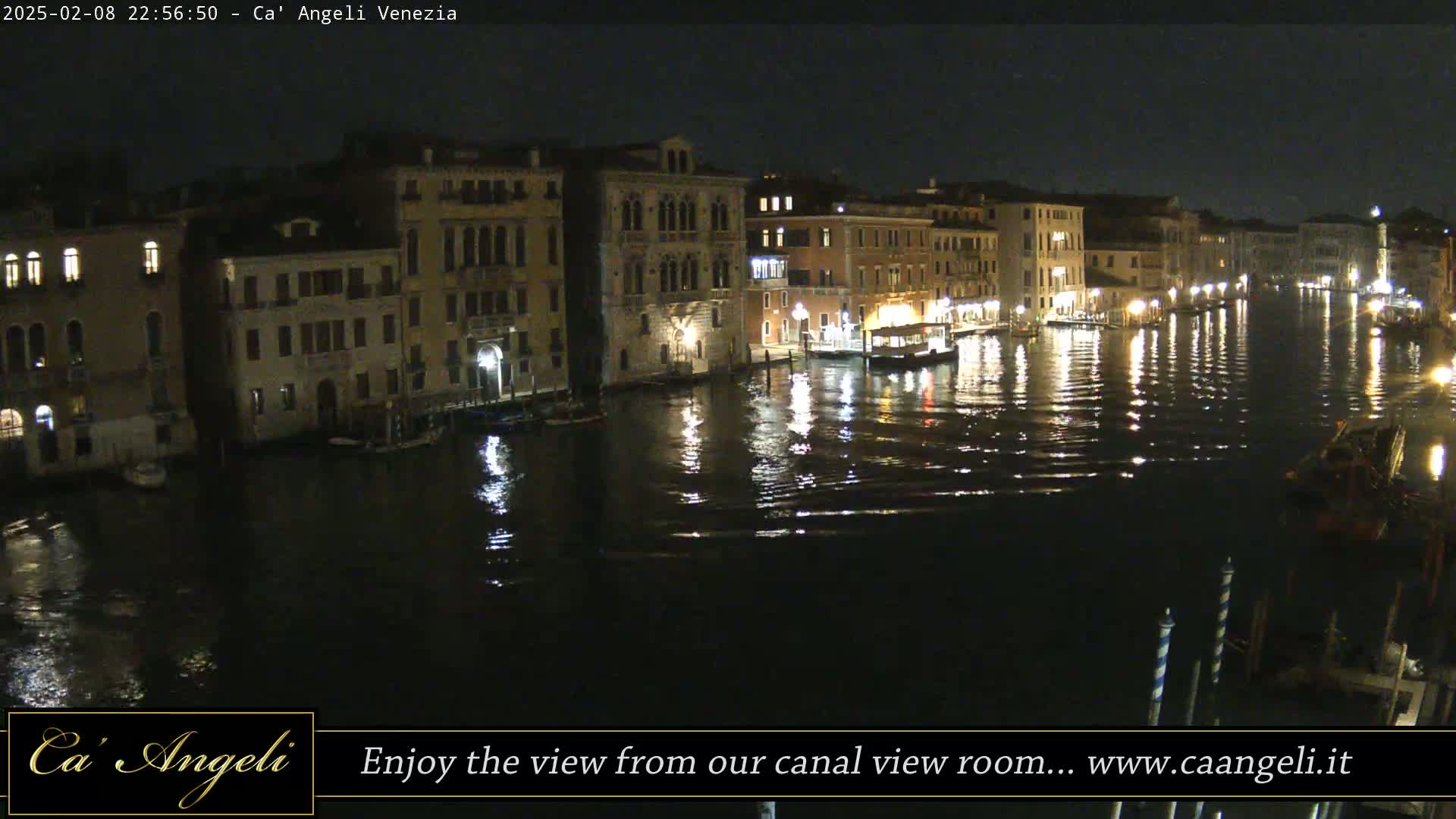 A nighttime view of illuminated buildings lining a calm canal in Venice.