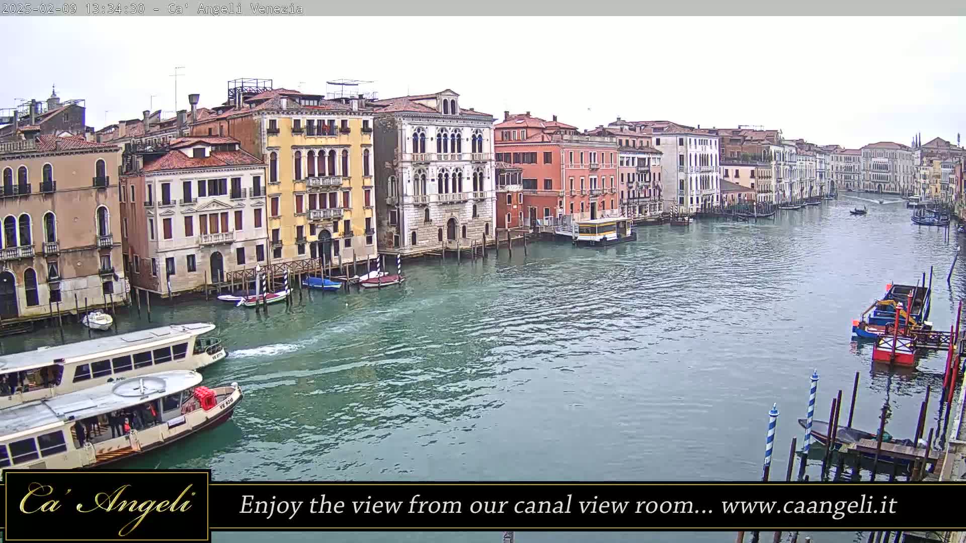 A wide shot shows a canal in Venice, Italy, on an overcast day with numerous boats and buildings lining the waterway.