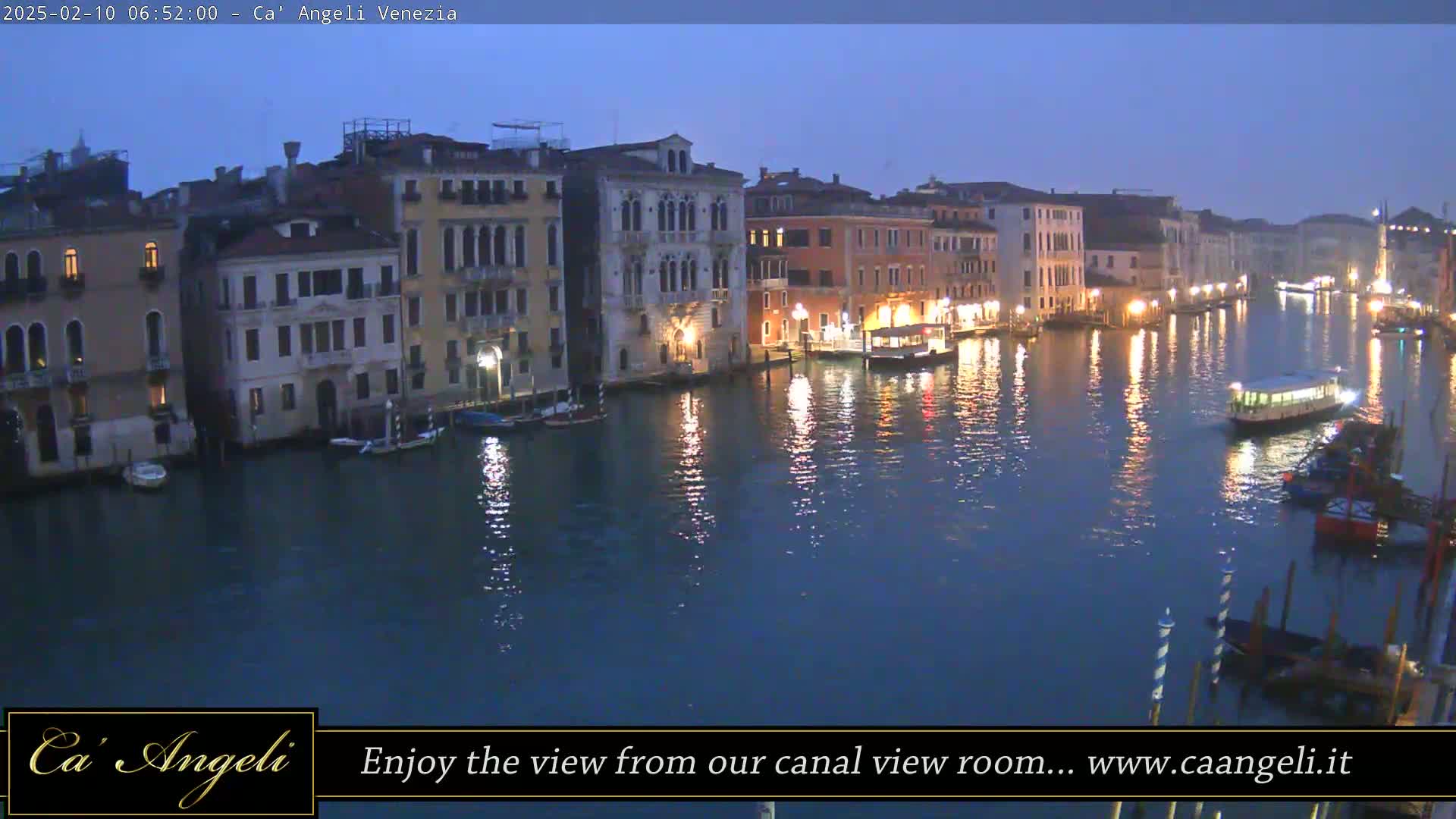 A twilight view of a canal in Venice, with buildings lining both sides and boats on the water.