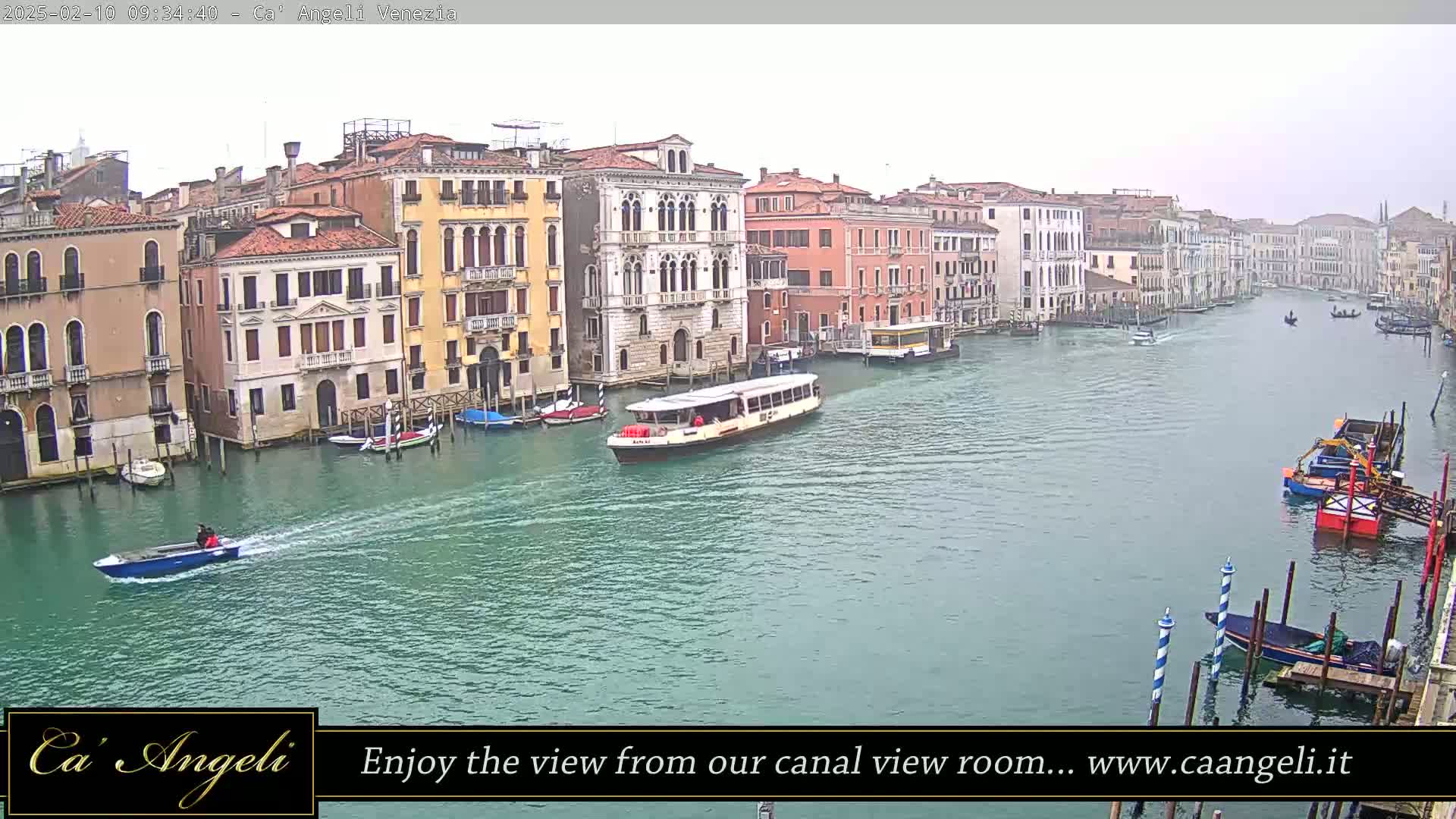 A wide shot shows a waterway in Venice, Italy, on an overcast day, with several boats and buildings lining the canal.