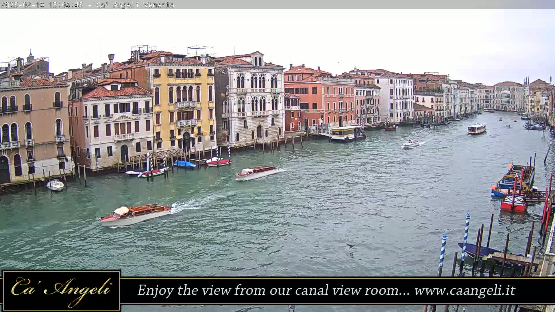 Several boats are traveling on a canal in Venice, alongside buildings on a cloudy day.