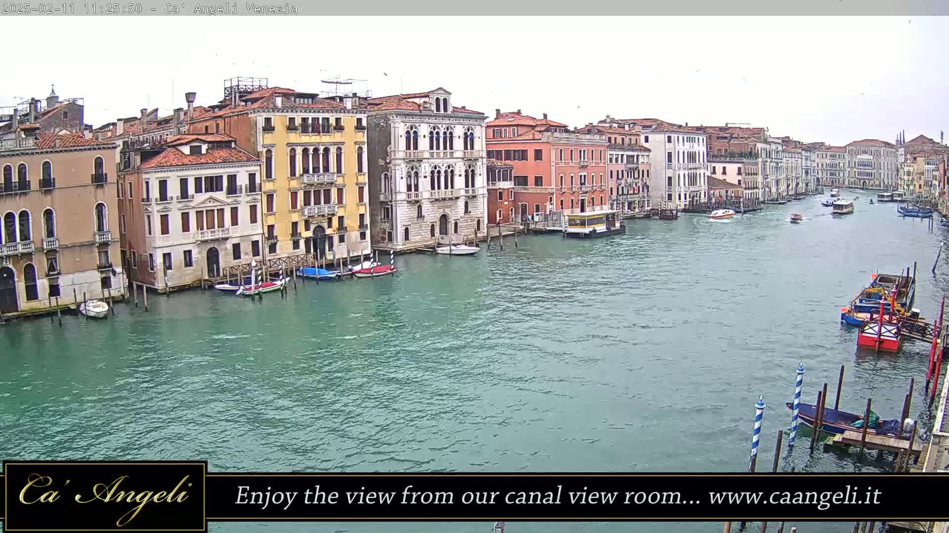 A wide shot of a canal in Venice, Italy, on an overcast day, shows numerous boats and buildings lining the waterway.