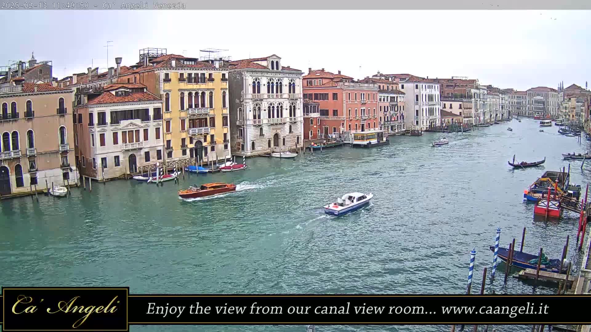 A wide shot shows a canal in Venice, Italy, on an overcast day with numerous boats and buildings lining the waterway.