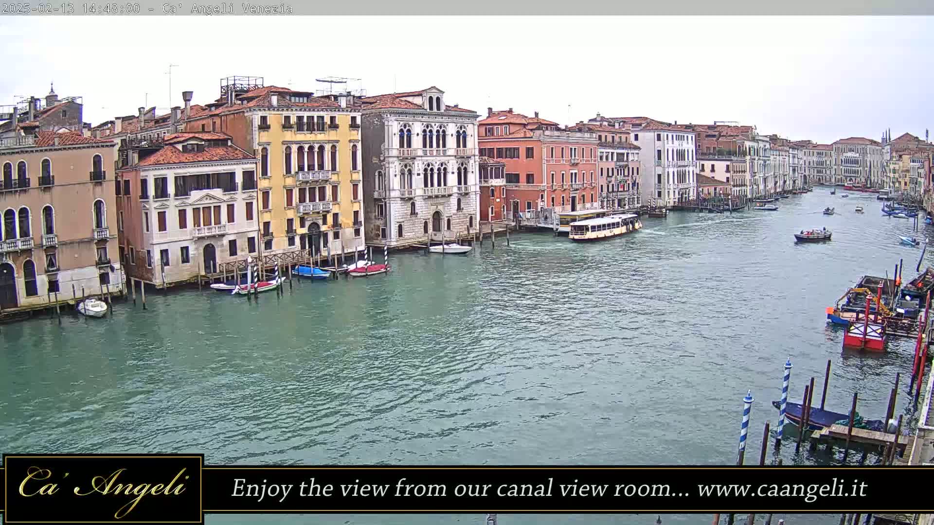 A wide shot shows a waterway in Venice with numerous boats and buildings lining the canals under an overcast sky.
