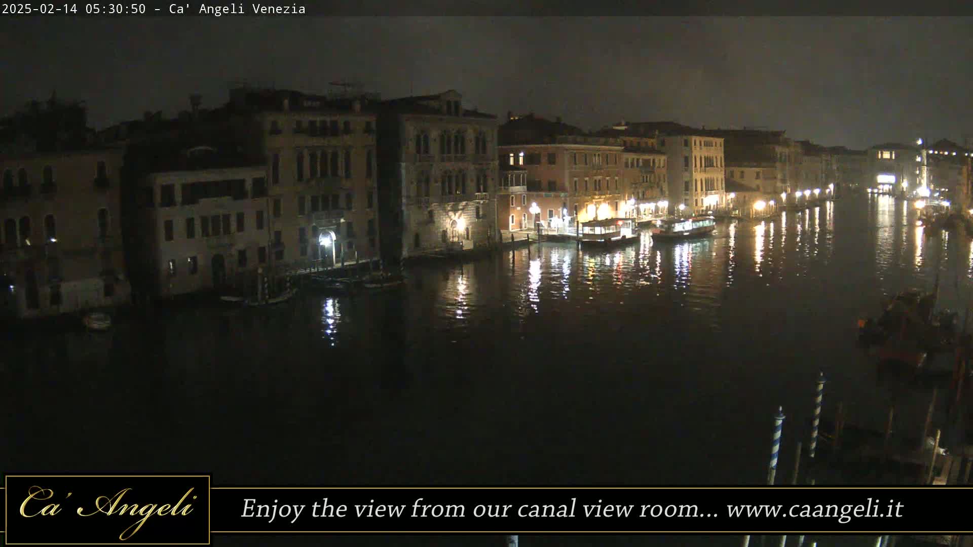 A nighttime view of a canal in Venice, with several buildings illuminated along the waterway.