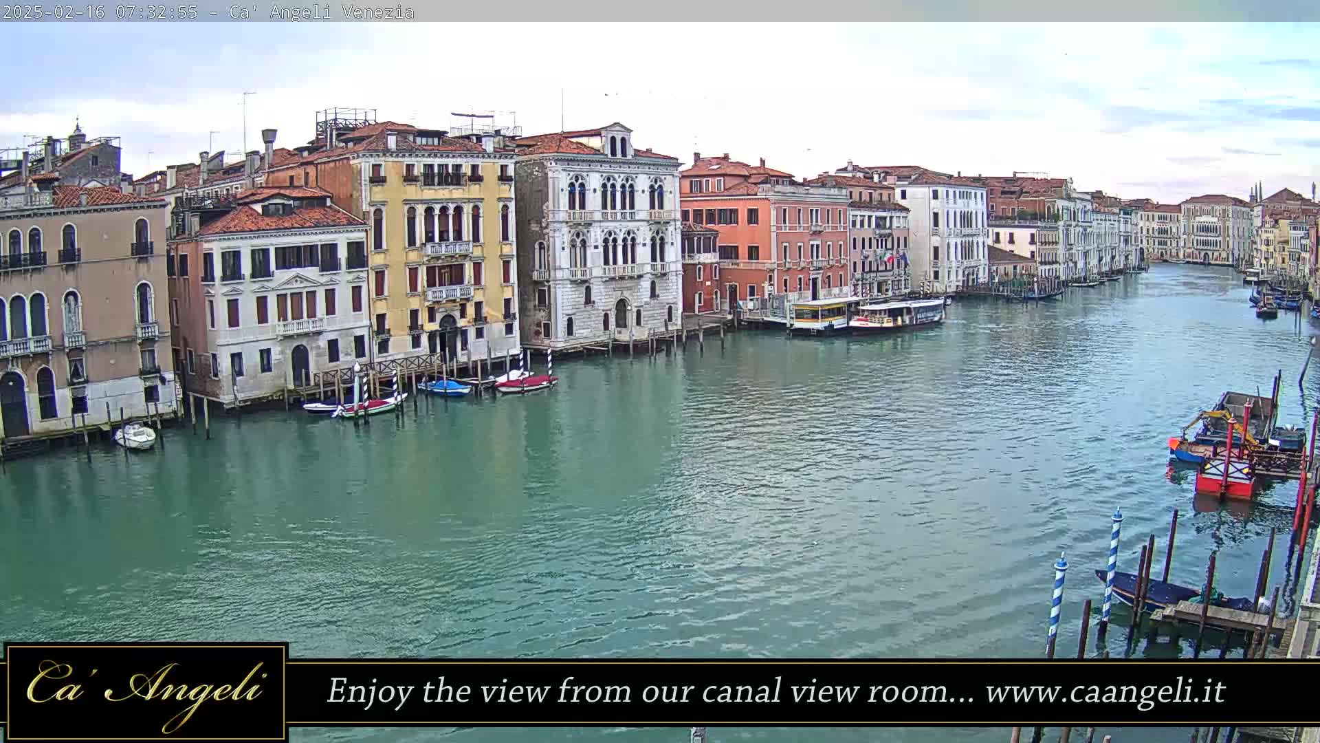 A wide canal in Venice, Italy, shows many colorful buildings lining its banks under a mostly cloudy sky, with several boats moored along the sides and a few traveling in the water.