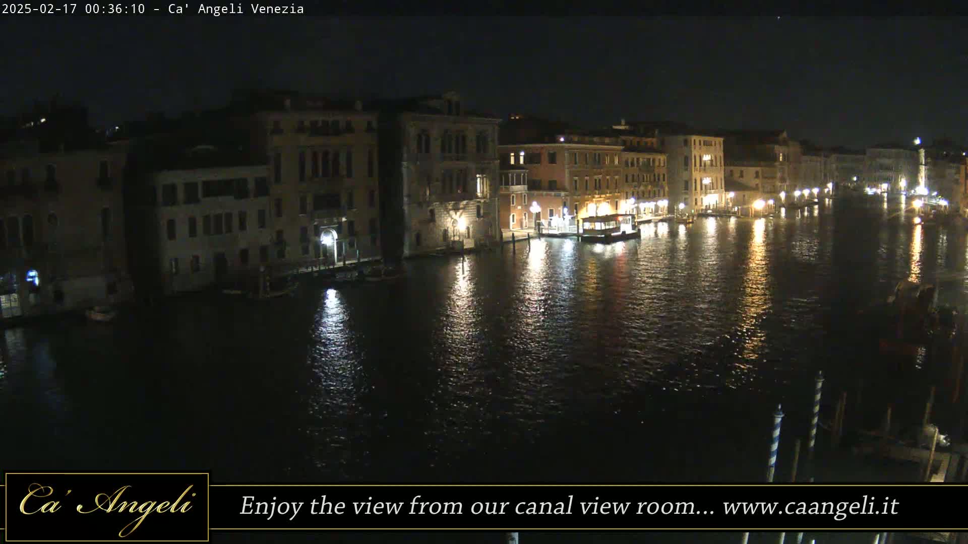 A nighttime view of a canal in Venice, with illuminated buildings lining the waterway and their lights reflected on the calm water.