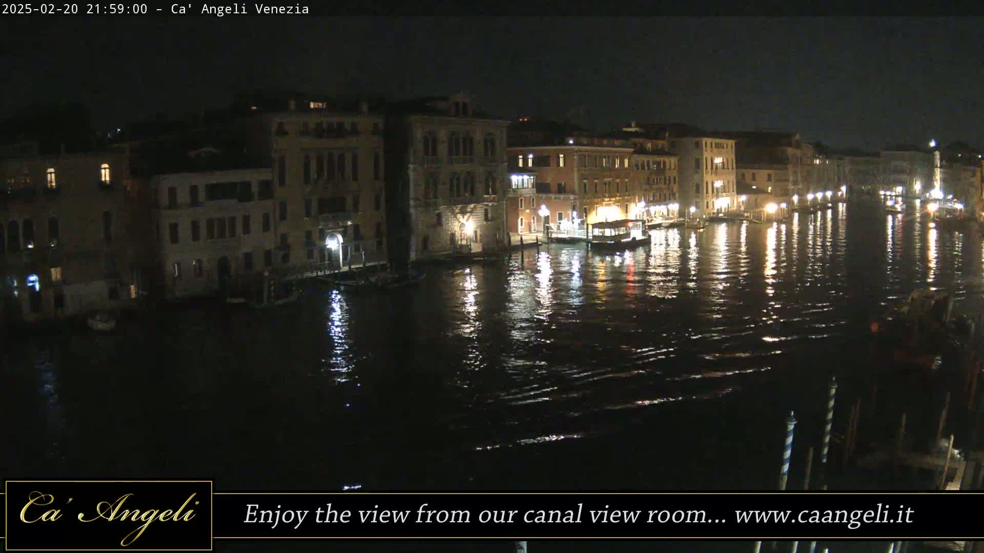 A nighttime view of a canal in Venice, with illuminated buildings lining the waterway and their lights reflecting on the dark water.