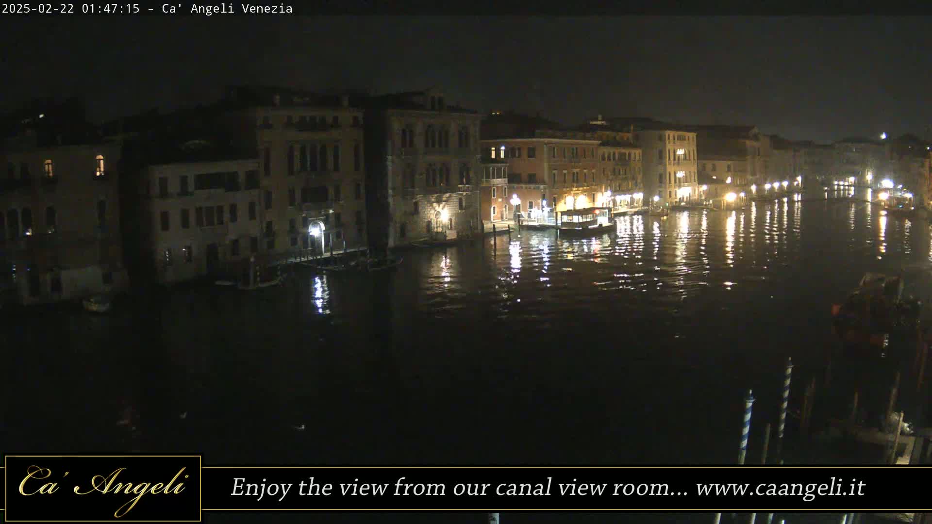 A nighttime view of a canal in Venice, with illuminated buildings lining the waterway and their lights reflecting on the dark water.