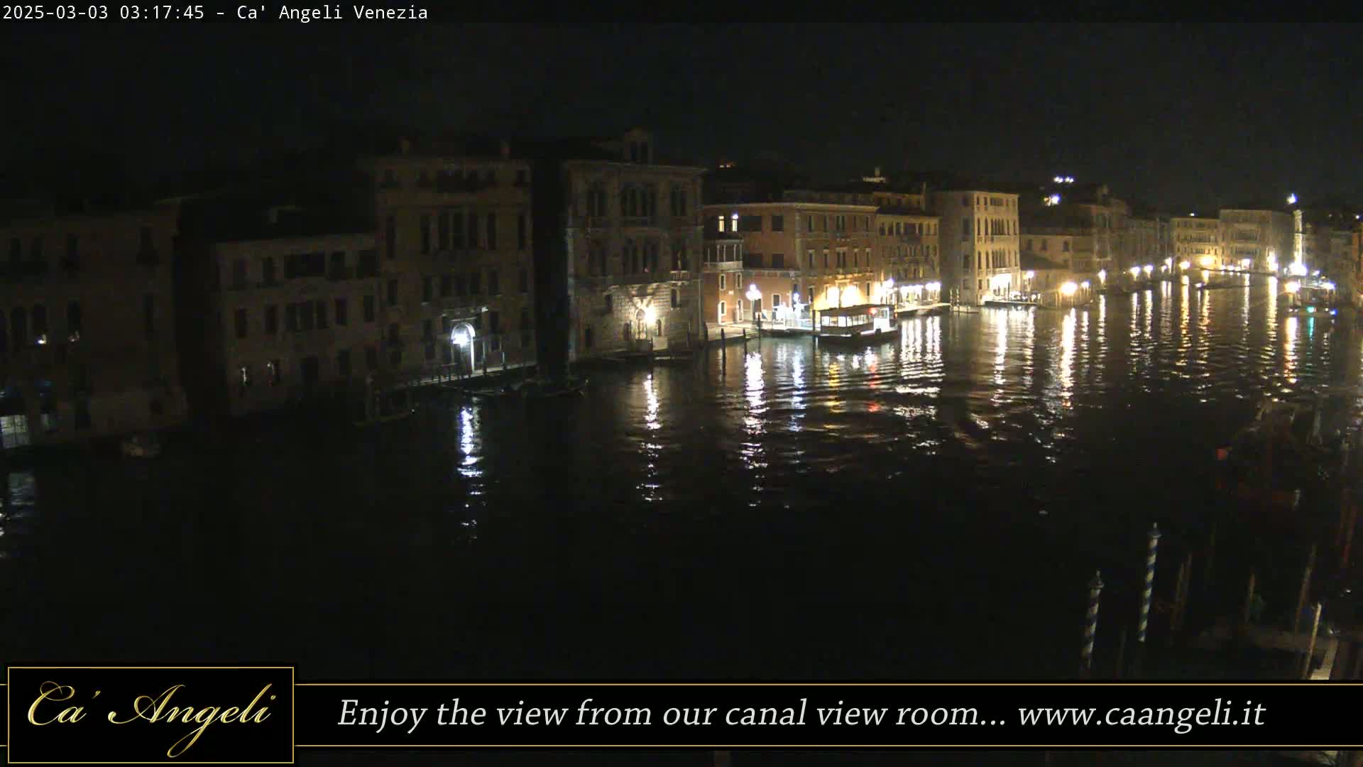 A nighttime view of a canal in Venice, Italy, with buildings lining the waterway, reflected in the calm water.
