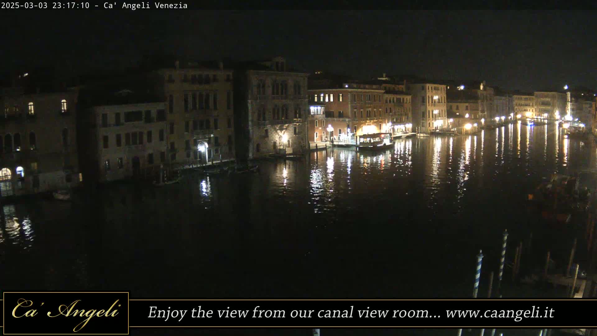 A nighttime view of a canal in Venice, with illuminated buildings reflected in the calm water.