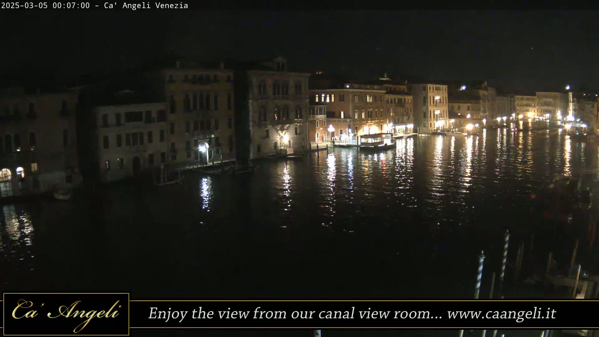 A nighttime view of a Venetian canal reflecting the lights from buildings along its banks.
