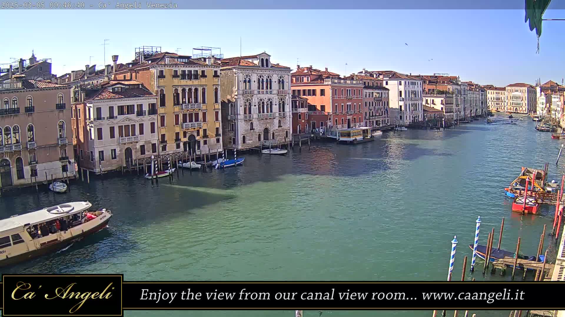 A waterway in Venice, Italy, on a sunny day, is lined with colorful buildings and several boats, some of which are docked.