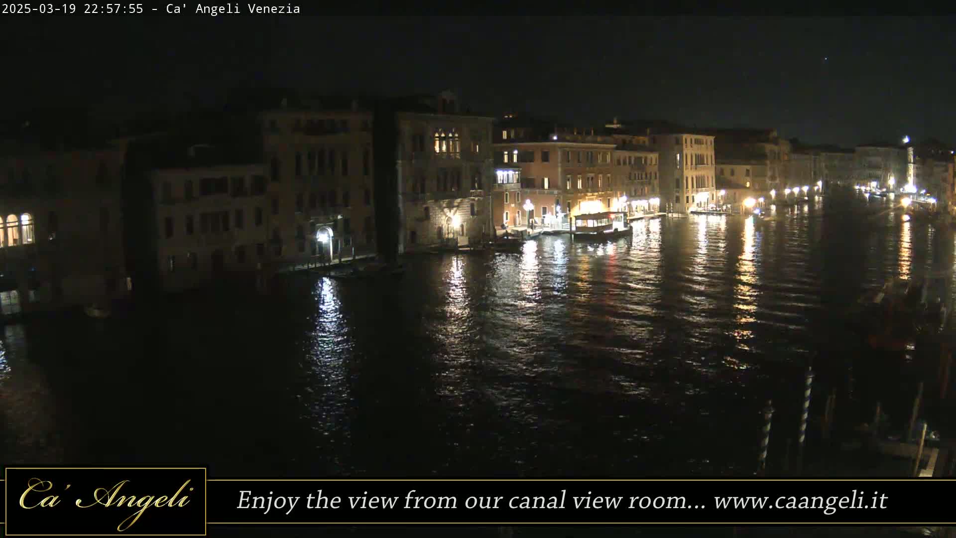 A nighttime view of a canal in Venice, Italy, with illuminated buildings lining the waterway.