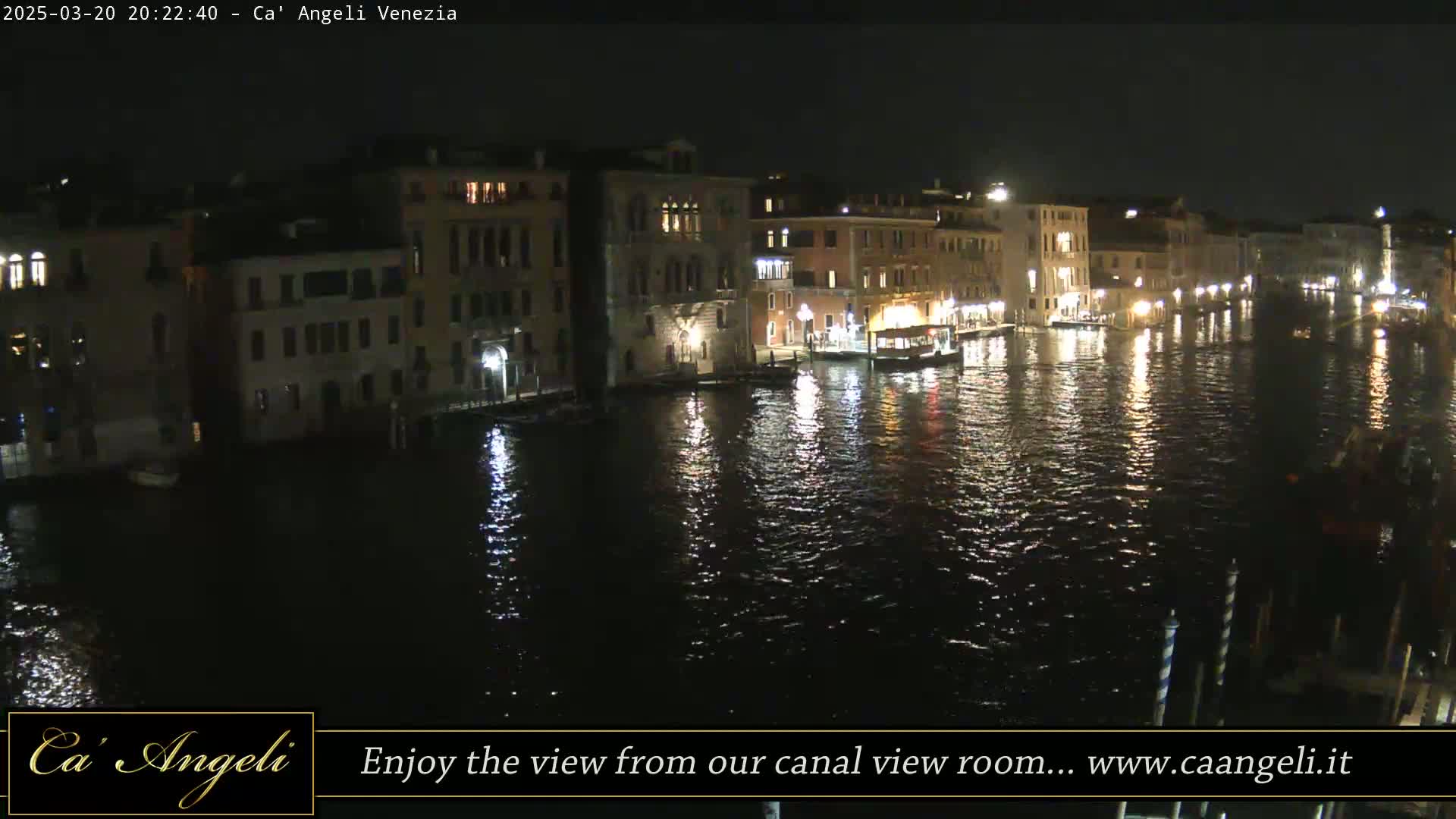 Nighttime view of a canal in Venice, with illuminated buildings lining the waterway and their lights reflecting on the water.