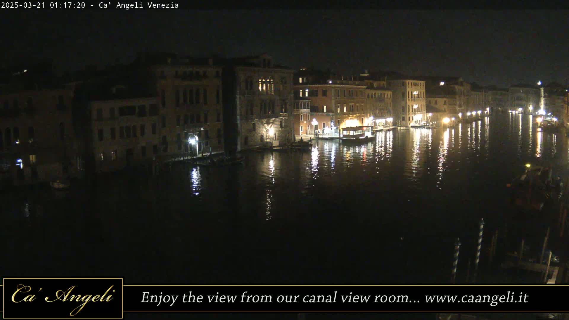 At night, a calm canal reflects the lights of buildings lining its banks.