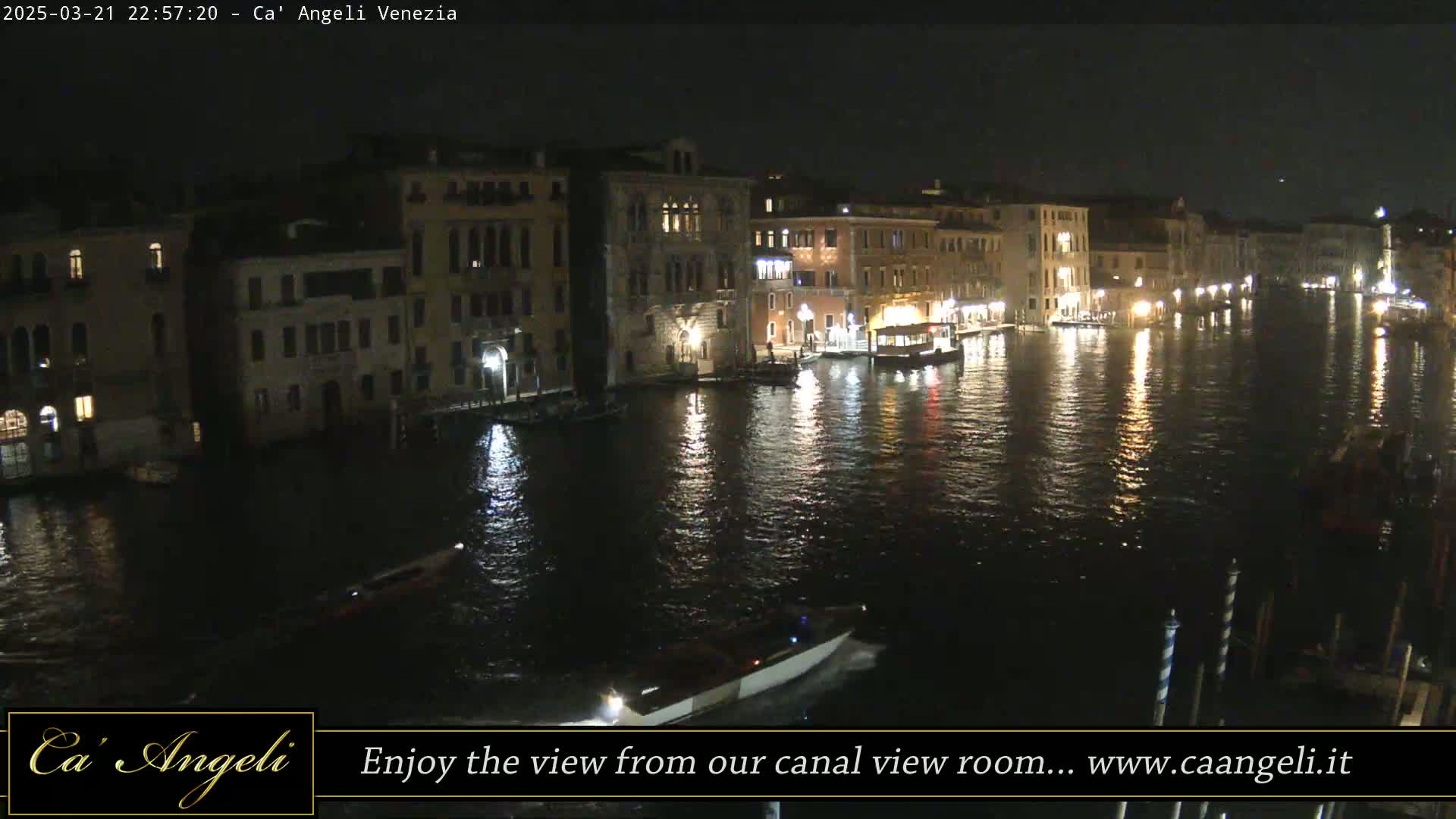 At night, illuminated buildings line a calm canal reflecting lights on its dark water.