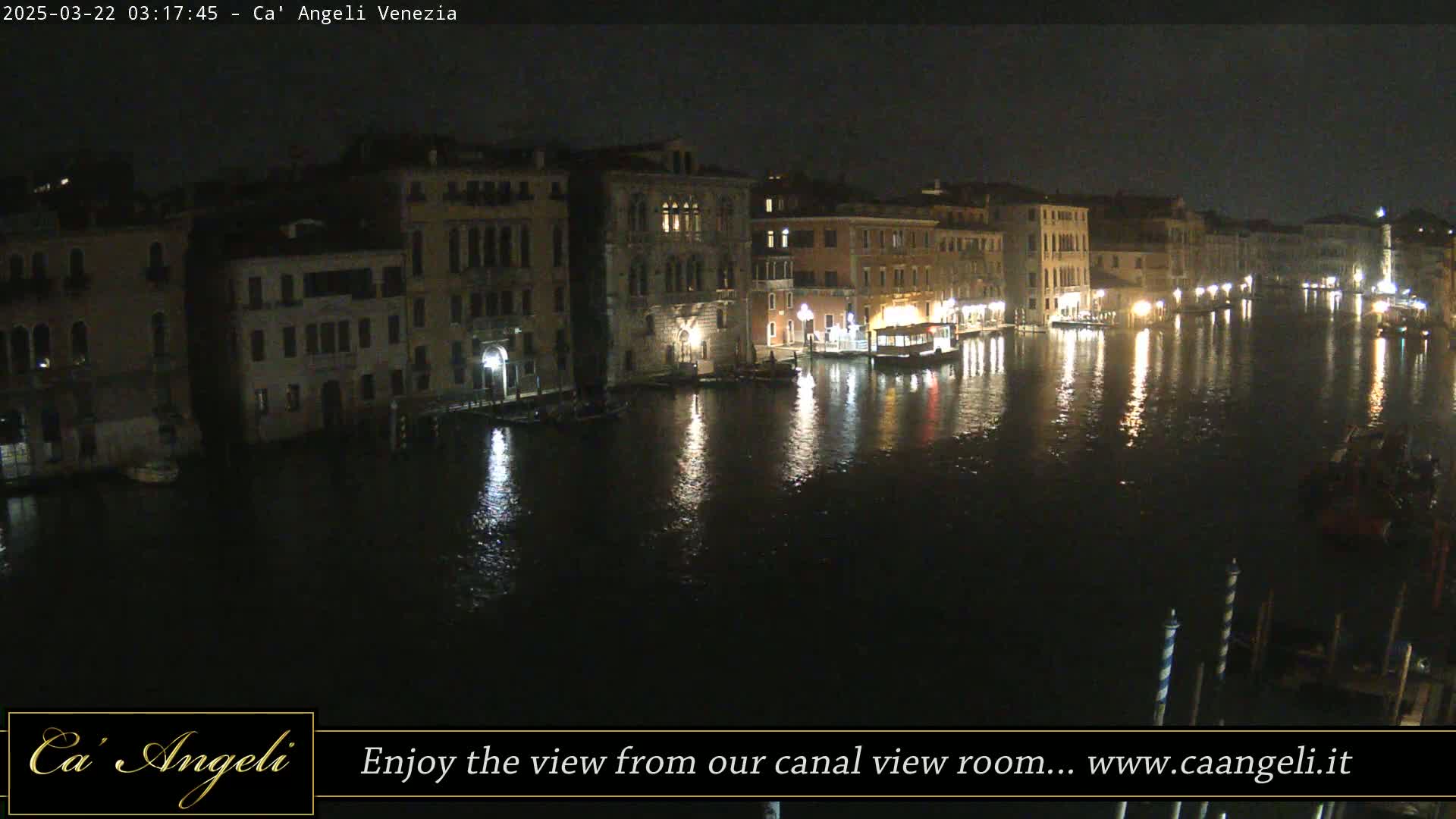A nighttime view of a canal in Venice, with buildings lining both sides, their lights reflecting on the dark water.