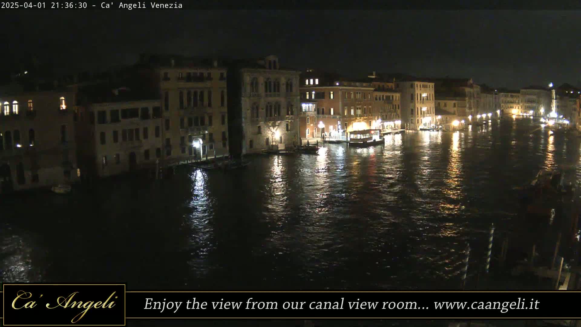 A nighttime view of illuminated buildings lining a calm canal in Venice.