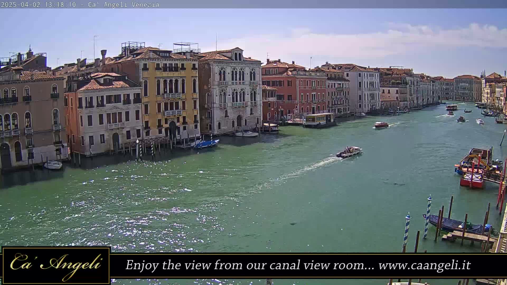 A sunny day in Venice shows a canal lined with colorful buildings and several boats.