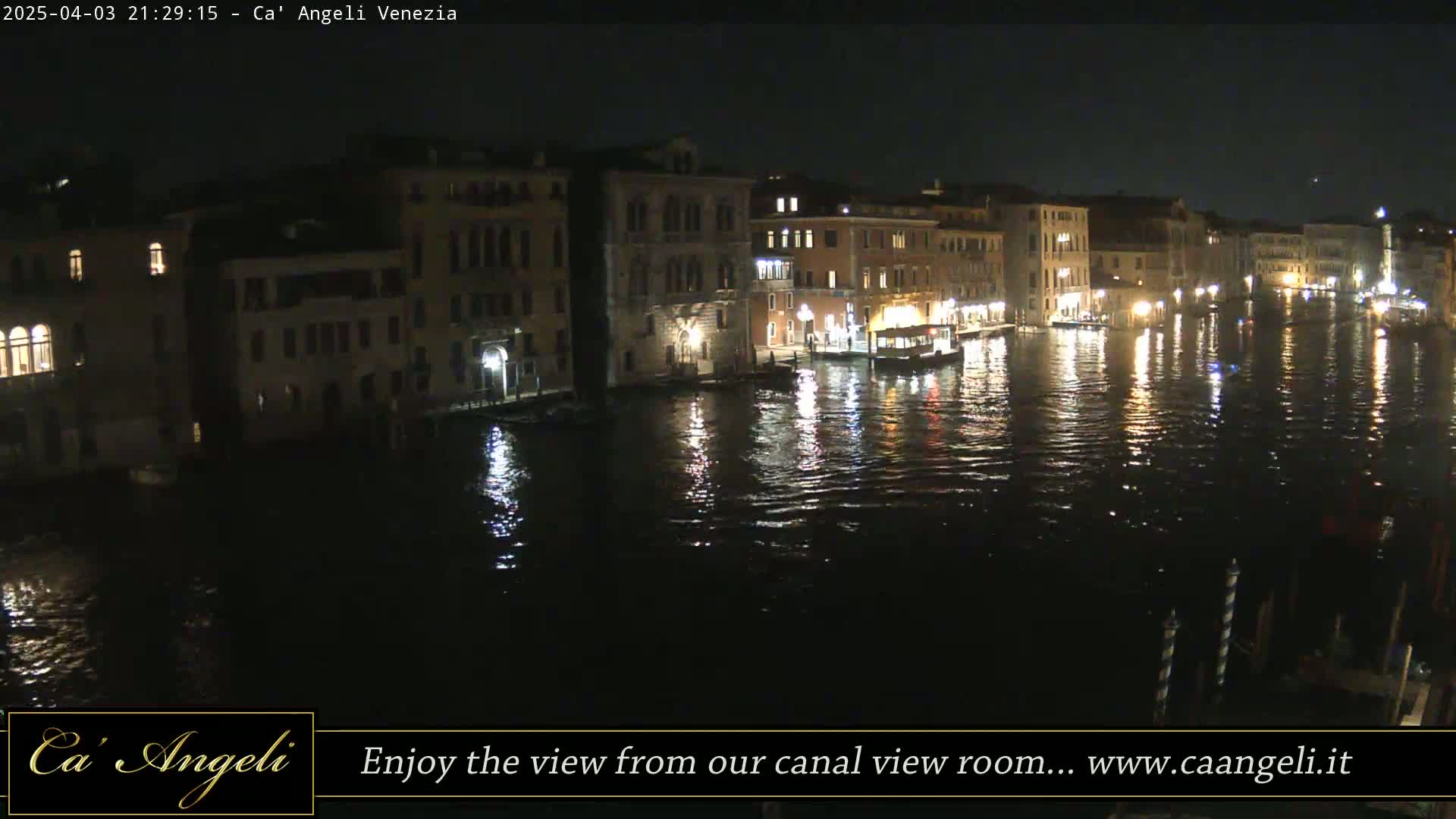 A nighttime view of a canal in Venice, with illuminated buildings lining the waterway and their reflections shimmering on the water's surface.