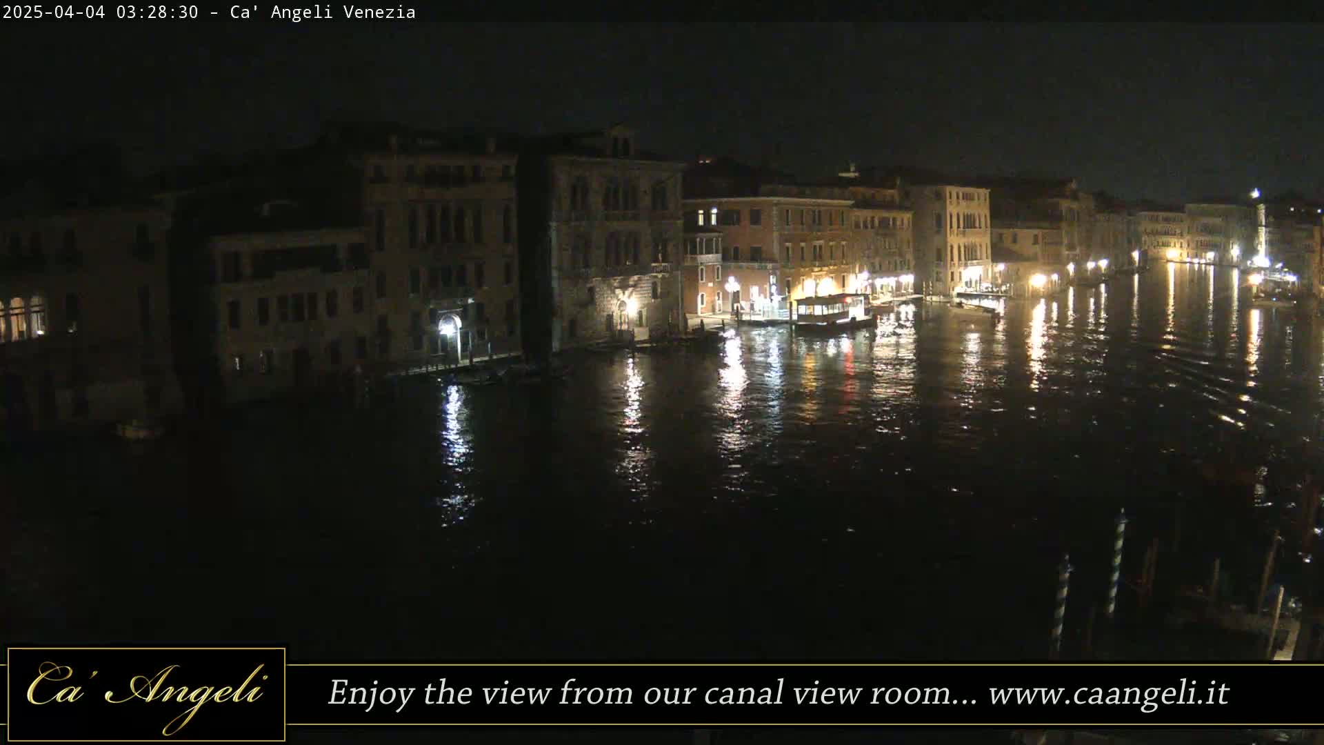 A nighttime view of a canal in Venice, with buildings lining the waterway and lights reflecting on the dark water.