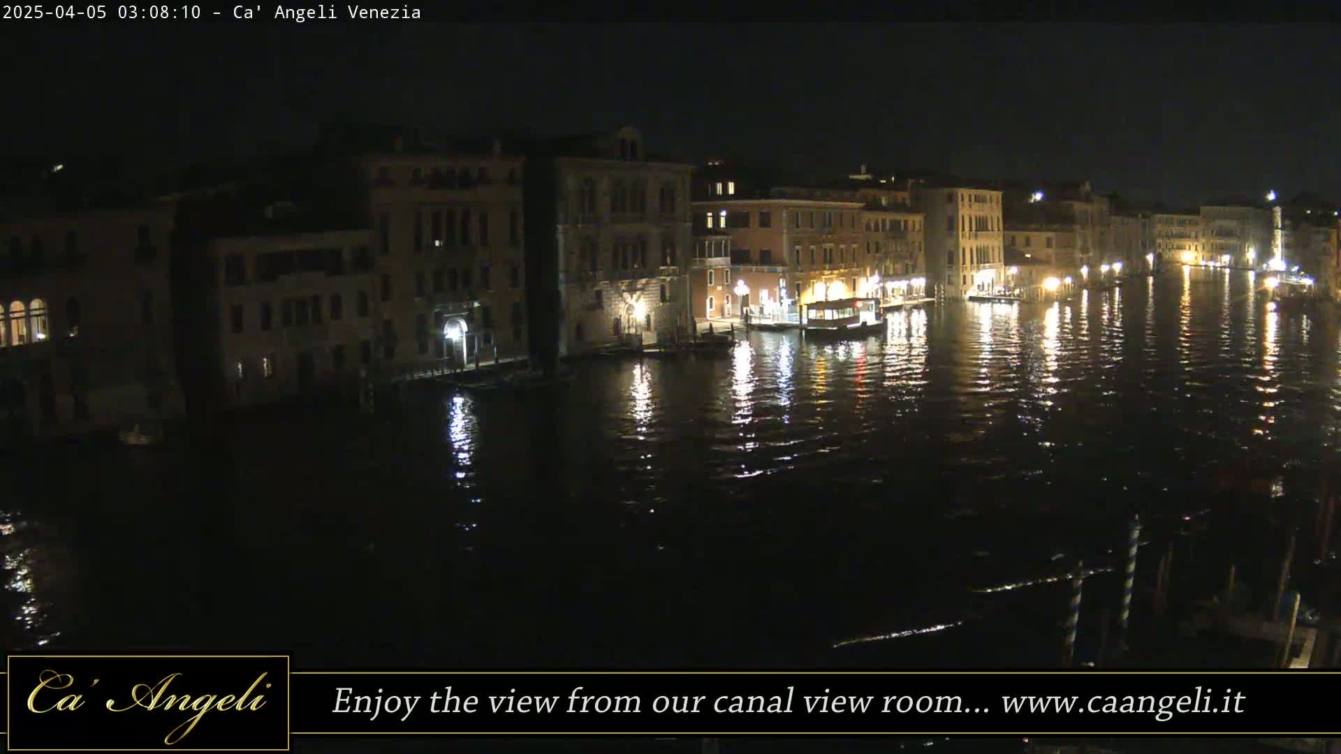 At night, a canal in Venice reflects the lights from buildings lining its banks.
