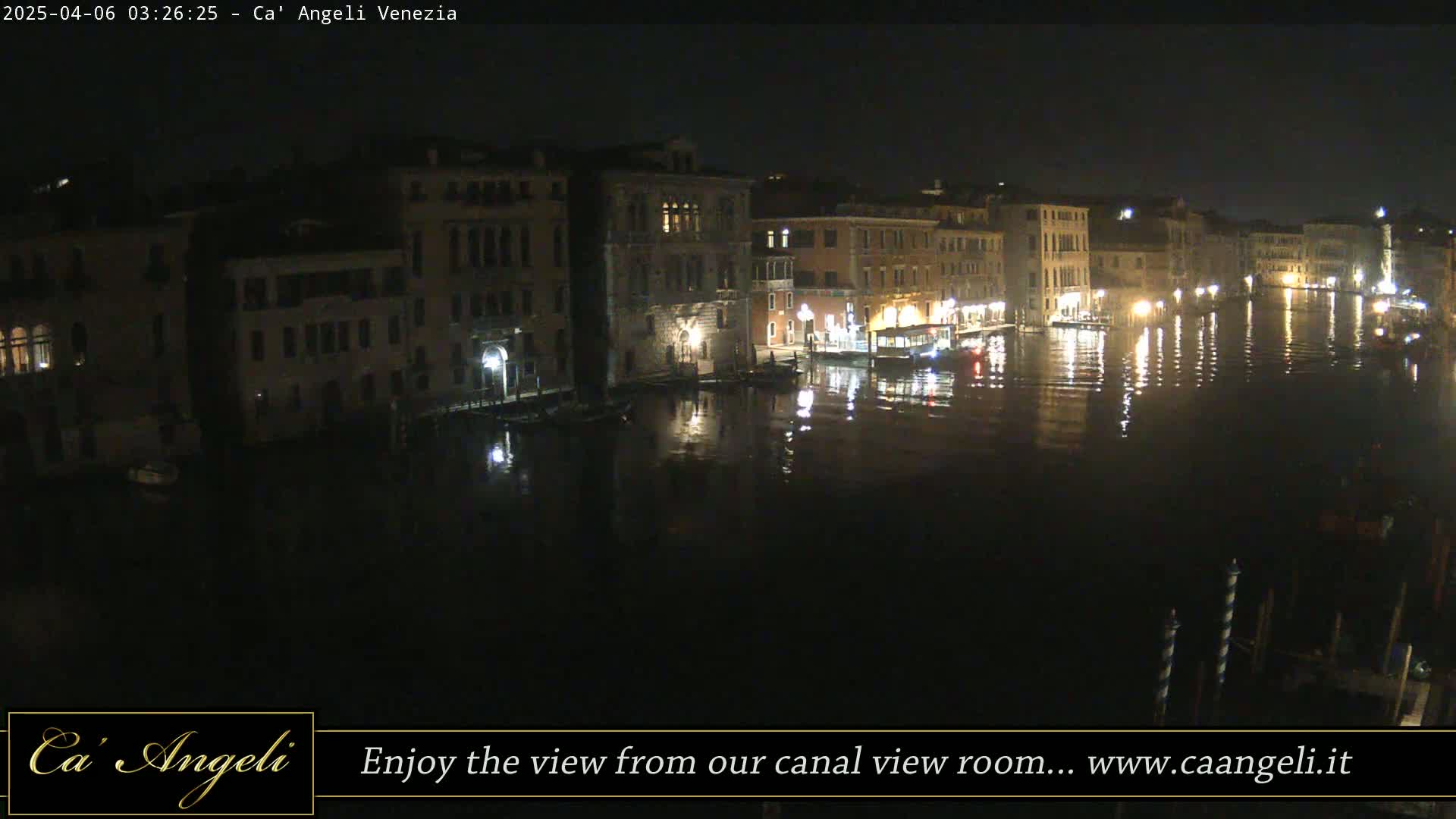 A nighttime view of a canal in Venice, with buildings lining both sides, reflecting in the dark water.
