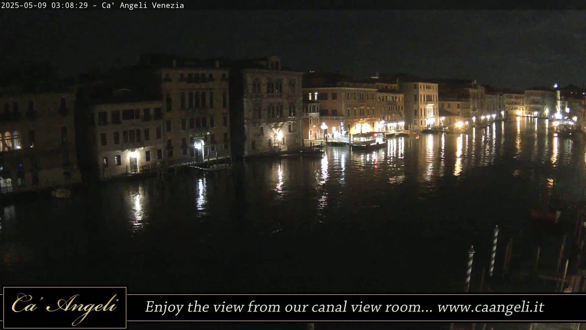 A nighttime view of a calm canal in Venice, with illuminated buildings lining the waterway.