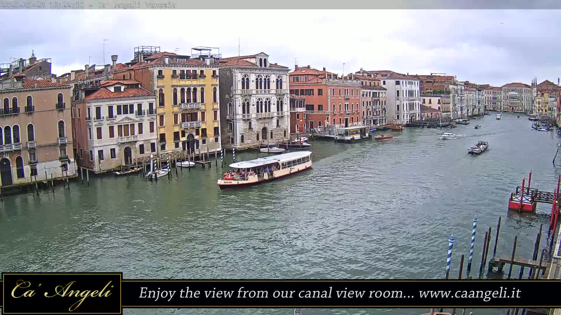 A waterway in Venice, under an overcast sky, shows several buildings lining the canal and boats traveling along the water.