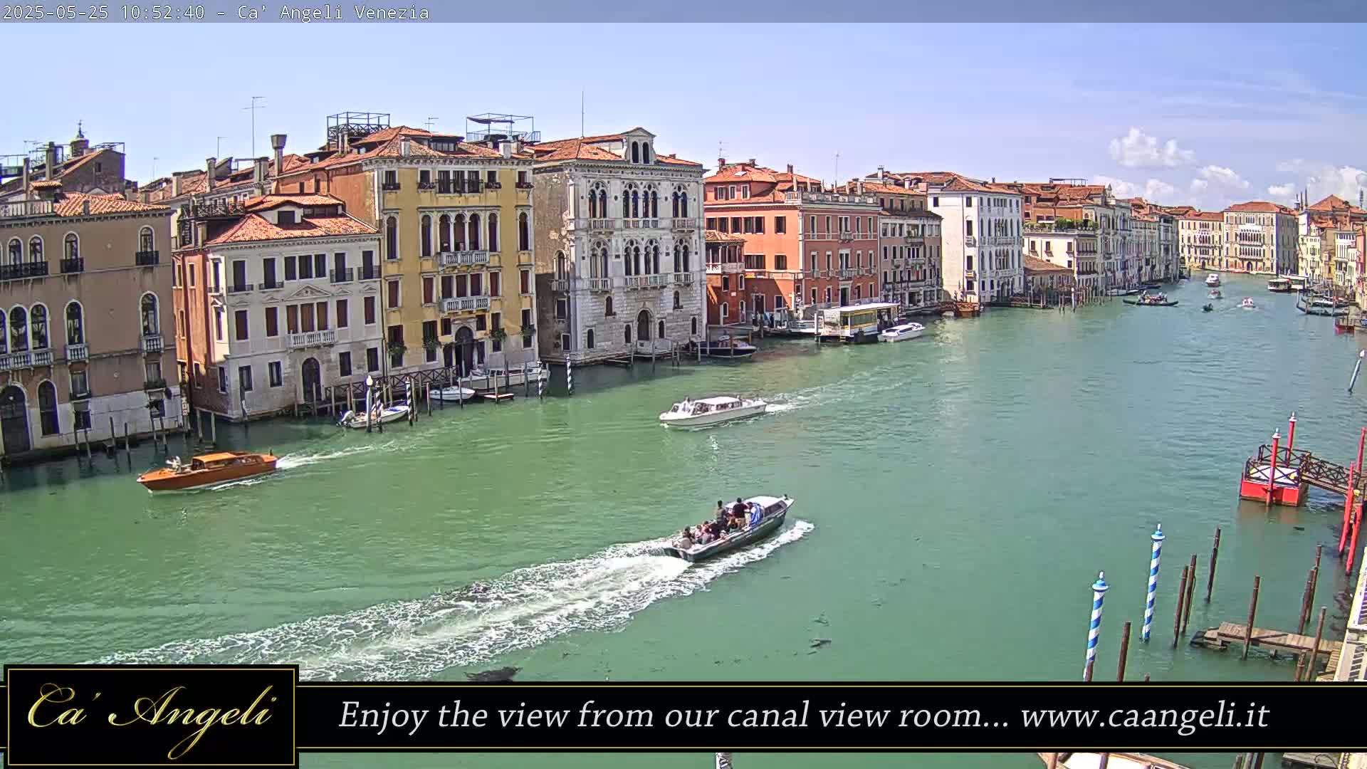 A sunny day in Venice shows several boats traveling on a wide canal lined with multi-story buildings.