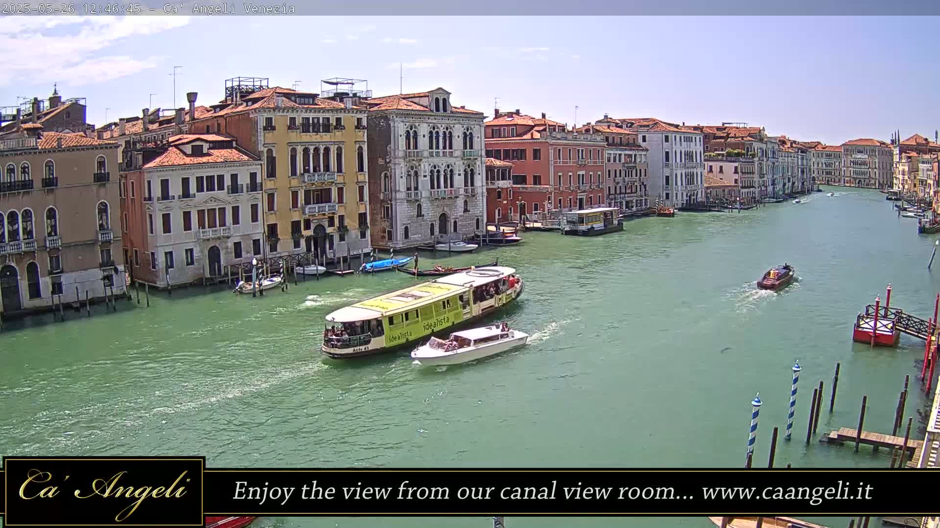 A waterway in Venice, under a mostly clear sky, is filled with boats, alongside buildings lining the canal.