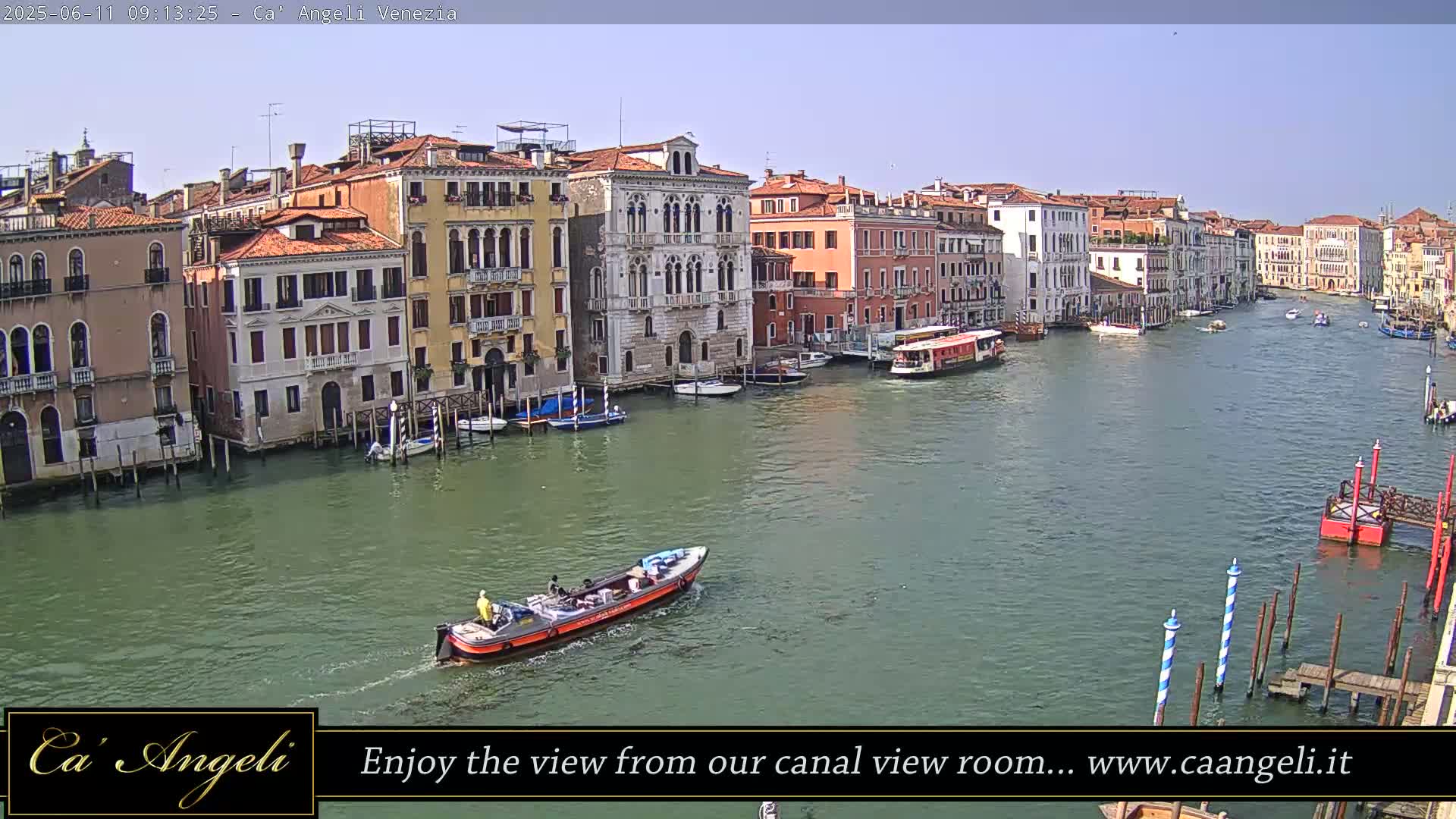 A sunny day in Venice shows a canal lined with buildings, several boats, and a water taxi.