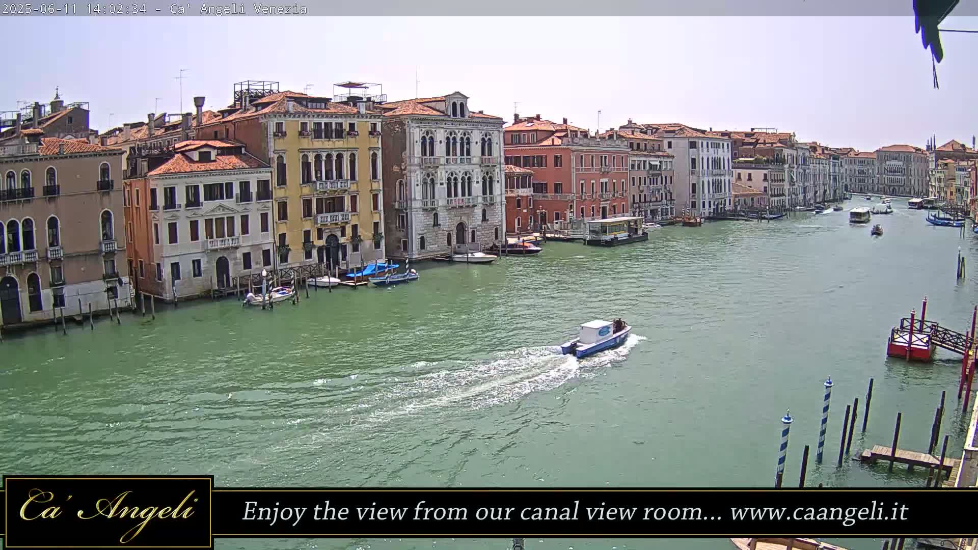 A wide shot shows a sunny day in Venice with a canal filled with boats, lined with colorful buildings on either side.