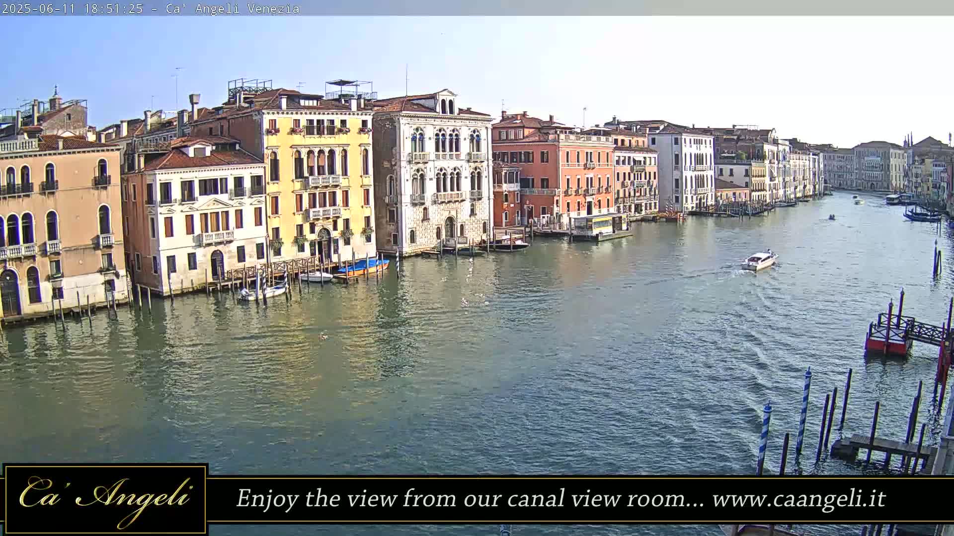 A sunny day in Venice shows a canal lined with colorful buildings and a few boats.