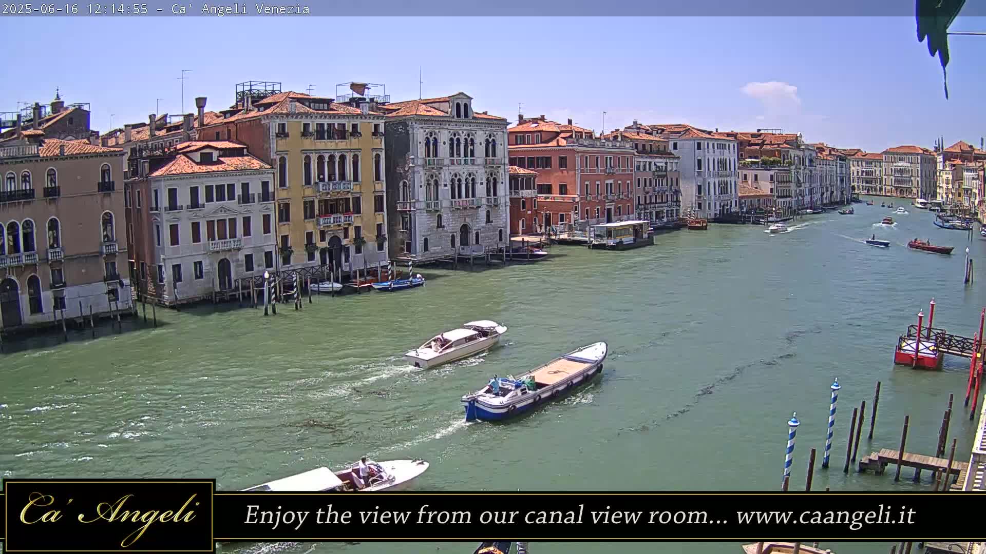 A sunny day in Venice shows several boats traveling down a canal lined with historic buildings.