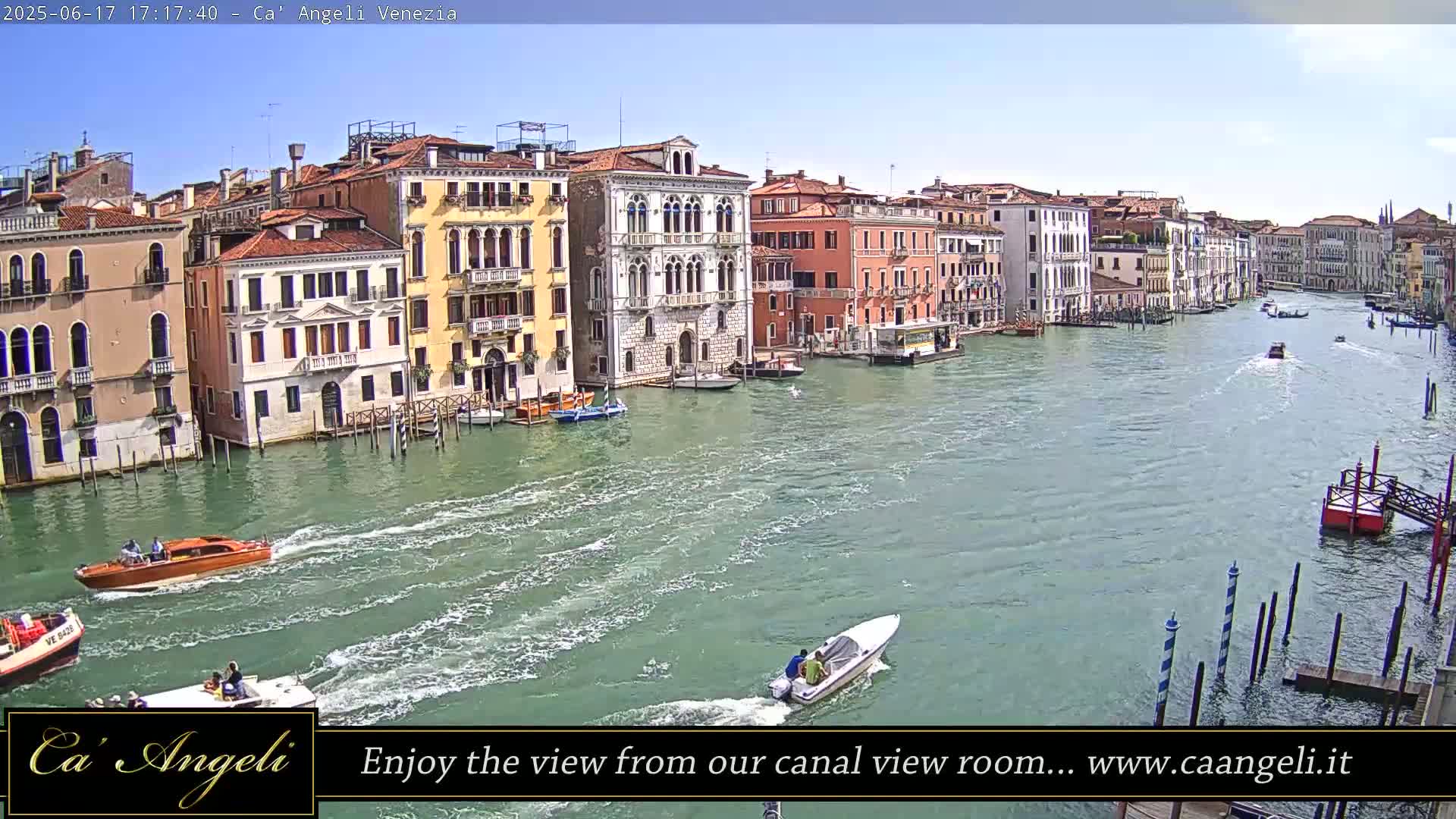 Several boats travel on a wide canal in Venice, Italy, under a sunny sky, passing colorful buildings along the waterway.