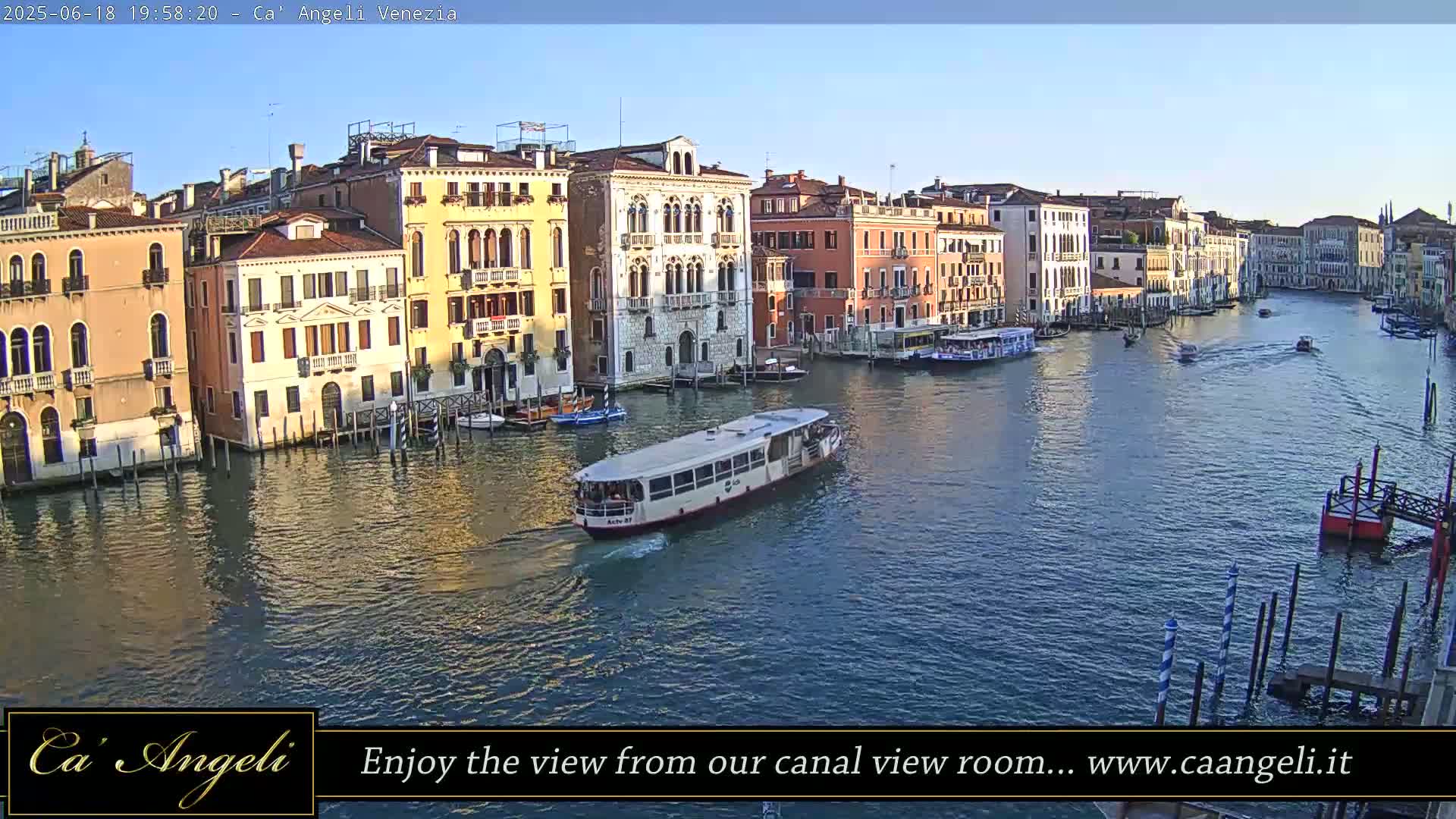 A waterway with several boats and colorful buildings lining the banks under a clear sky.