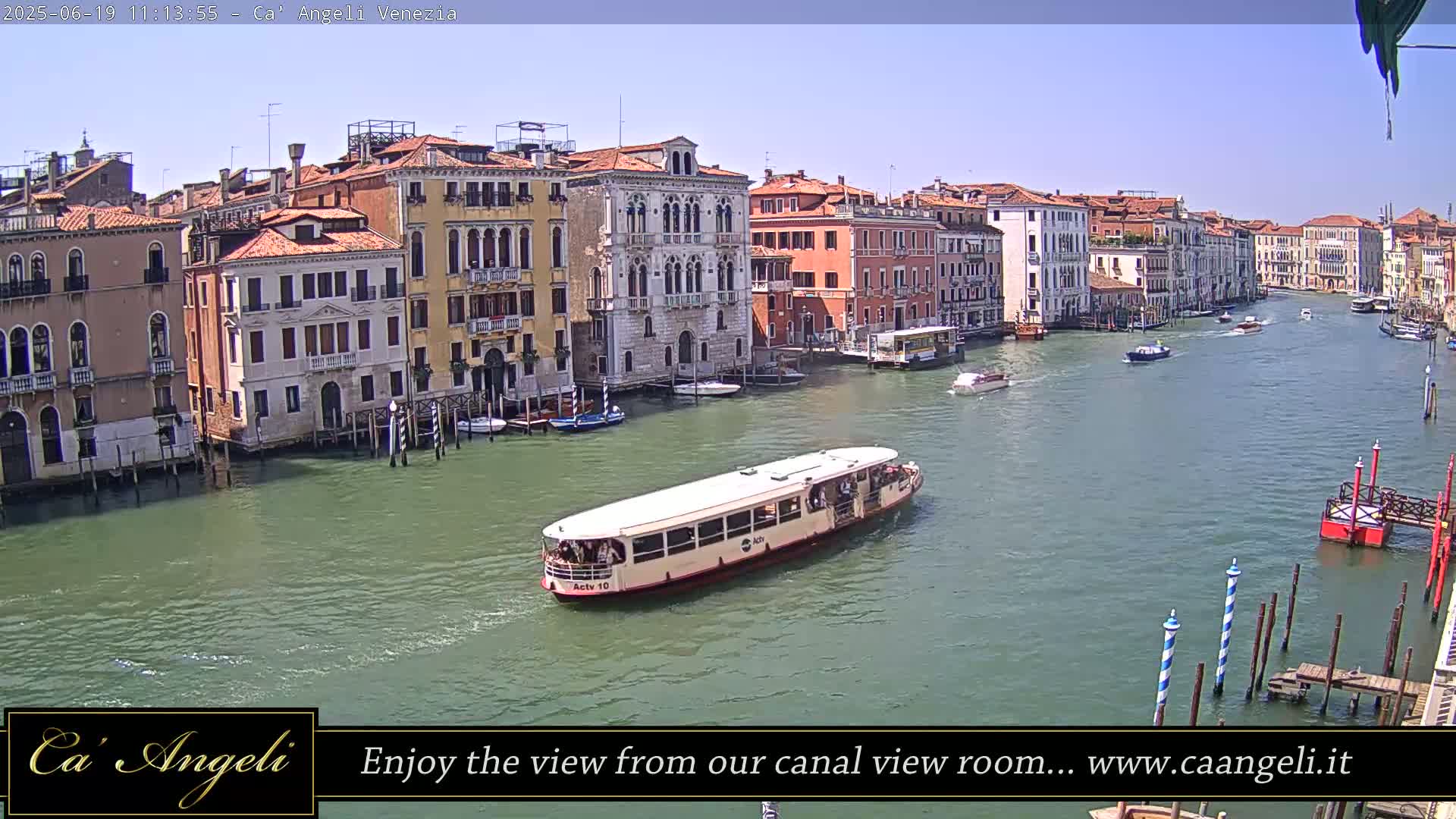 A water taxi travels down a canal in Venice, Italy, on a sunny day, passing colorful buildings lining the waterway.