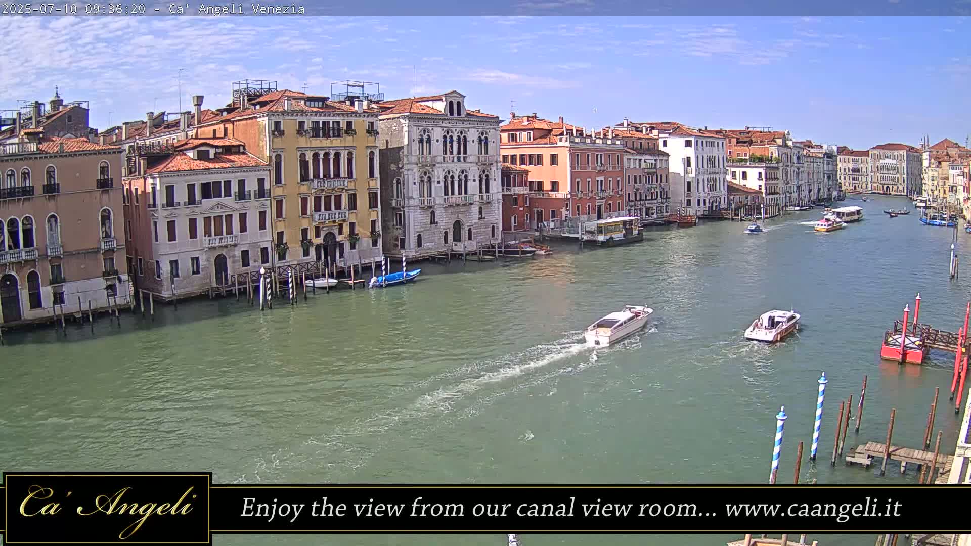 A sunny day in Venice shows several boats traveling on a canal lined with historic buildings.
