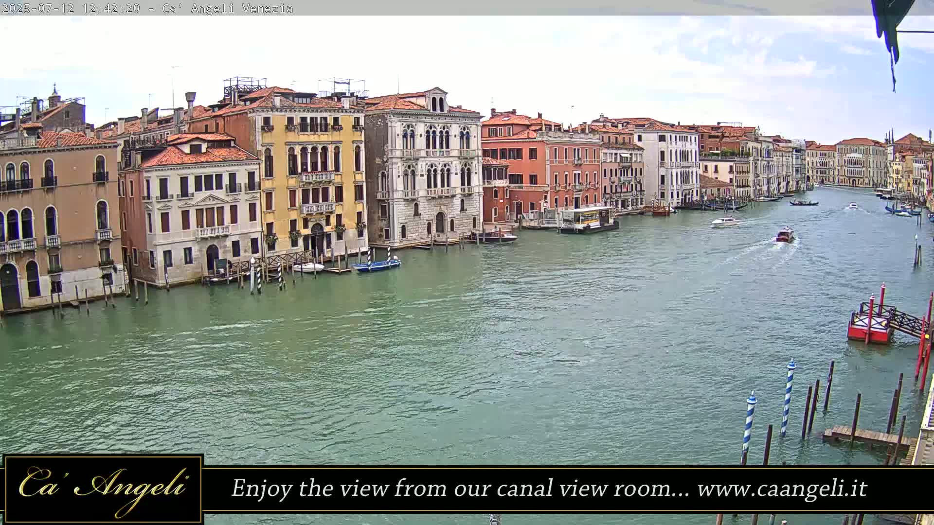 A sunny day in Venice shows several boats traveling on a canal lined with historic buildings.